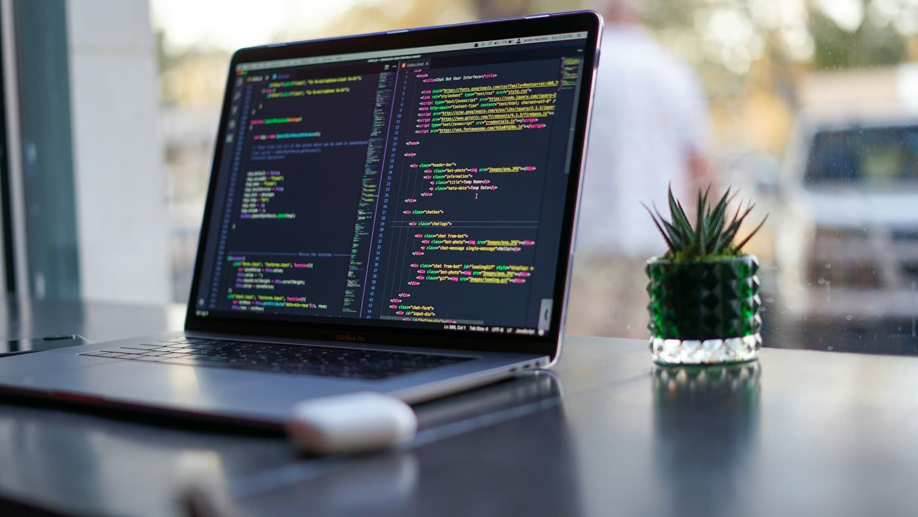 A developer's laptop showing code by a bright window